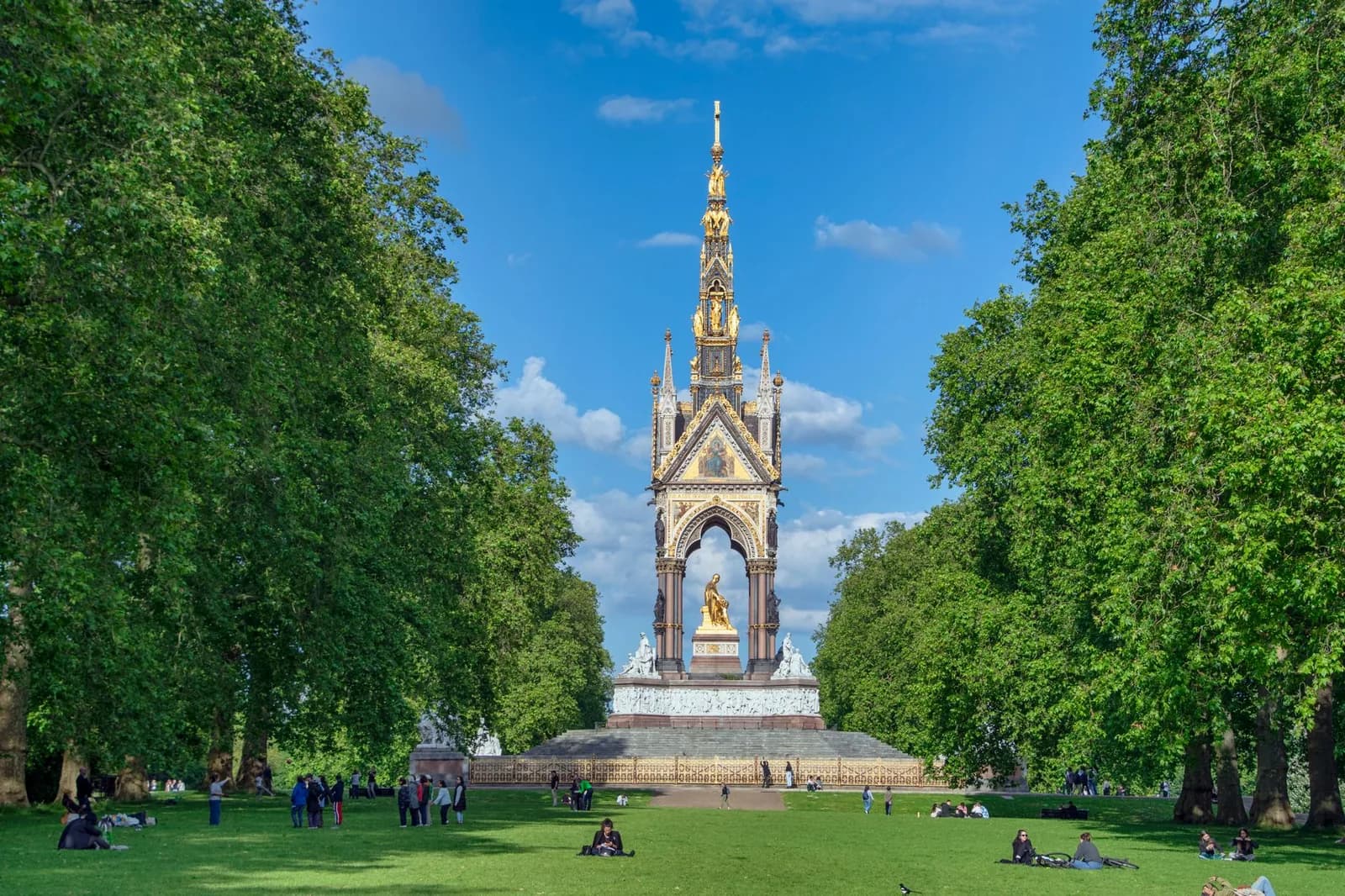 L'Albert Memorial entre deux rangées d'arbres, promeneurs sur la pelouse de Kensington Gardens