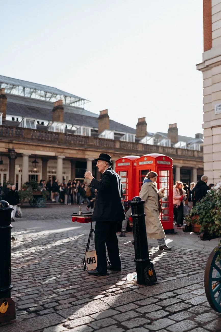 Artiste de rue en costume sur la Piazza de Covent Garden, devant des cabines téléphoniques rouges