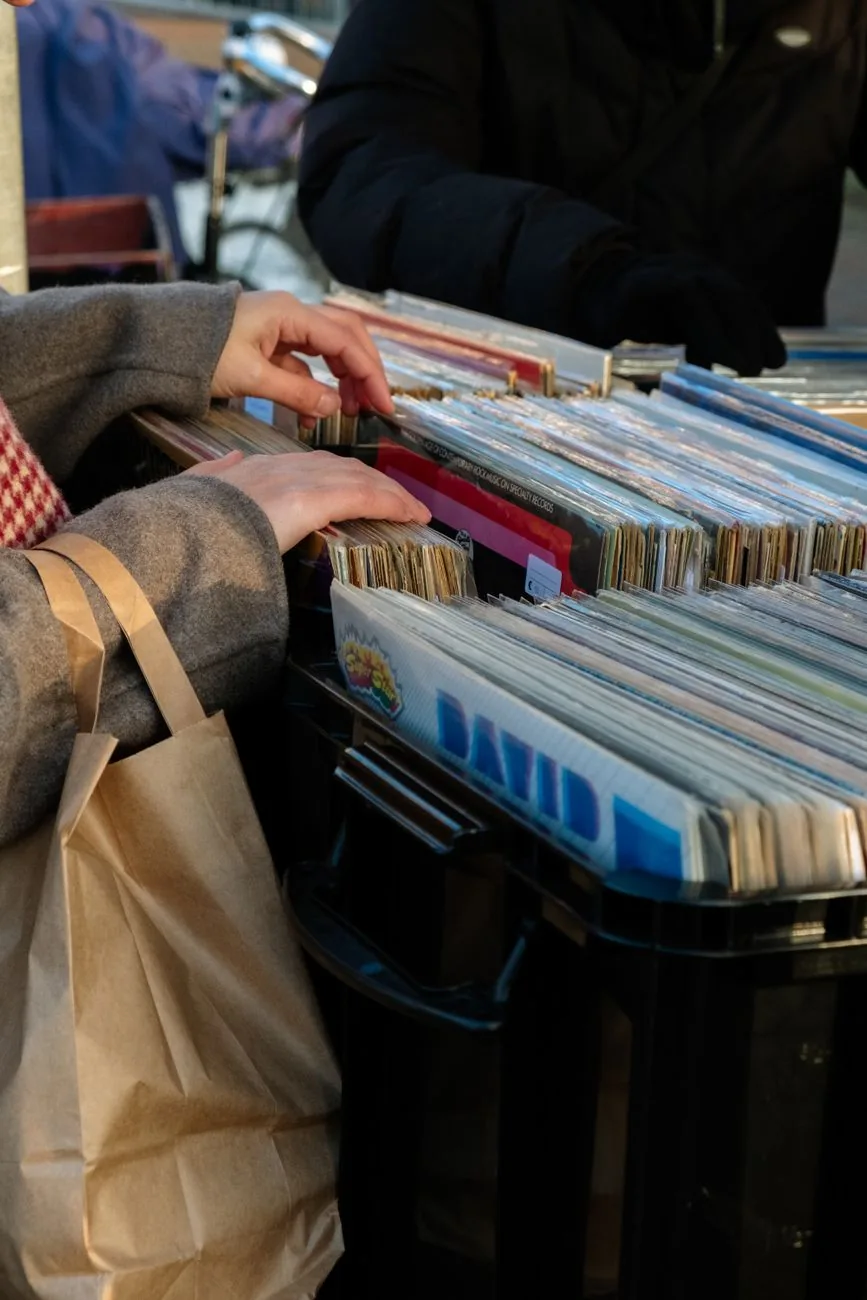 Mains fouillant des bacs à disques vinyle sur un étal de marché