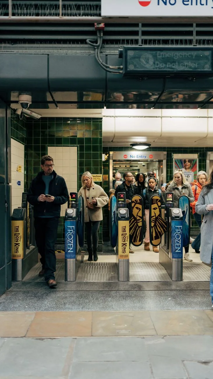 Voyageurs franchissant les barrières de validation aux lecteurs jaunes d'une station du métro de Londres