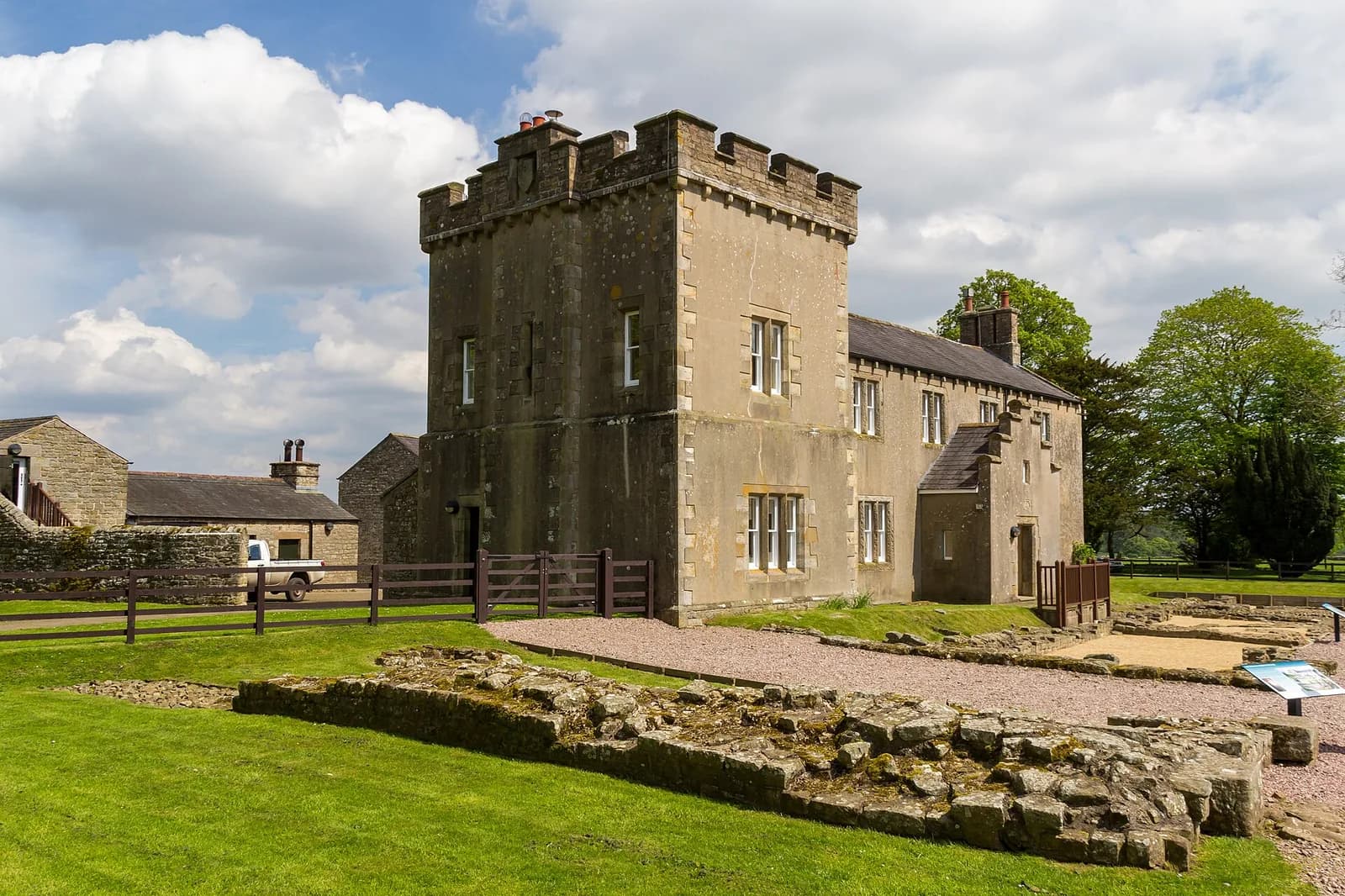 Vestiges du fort romain de Birdoswald, en Cumbria, devant un bâtiment en pierre à tour crénelée