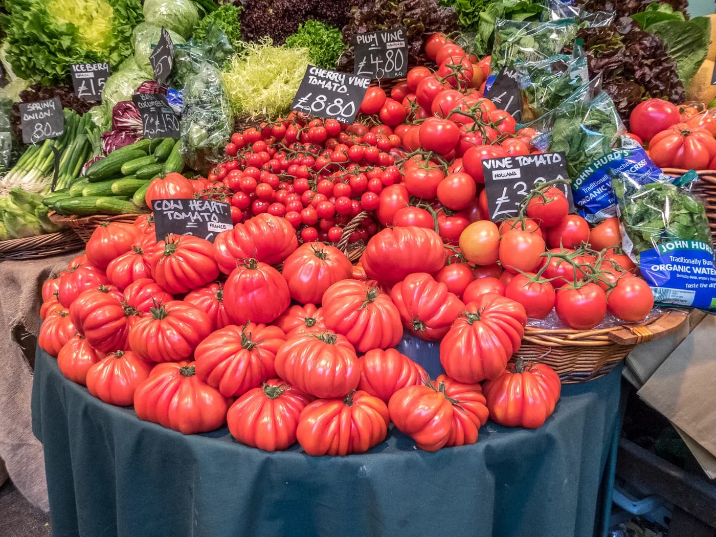 Étal de tomates côtelées, légumes et salades sous les halles de Borough Market, à Londres