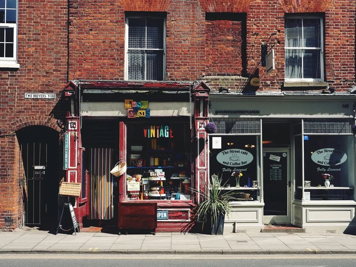 Rue commerçante aux façades de brique avec une petite boutique indépendante et un café