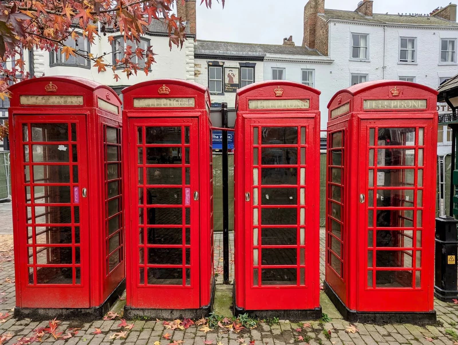 Cabines téléphoniques rouges britanniques alignées devant des façades blanches