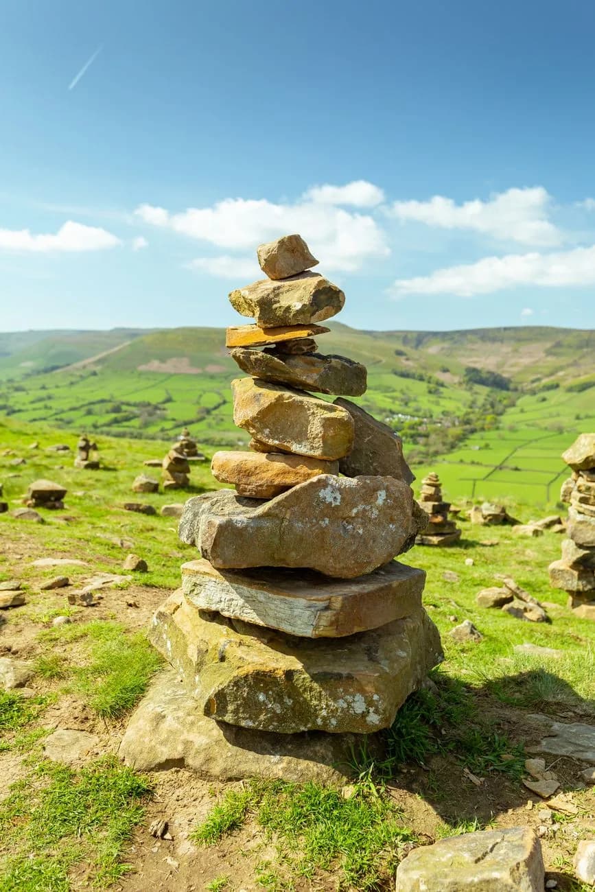 Cairn de pierres empilées au-dessus d'une vallée aux champs cloisonnés de murets
