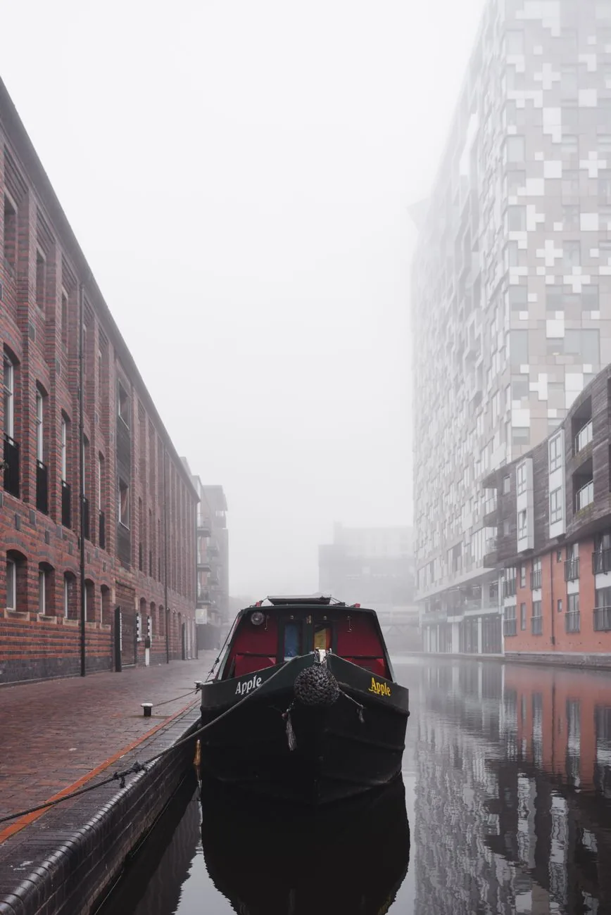 Péniche amarrée sur un canal de Birmingham, entre entrepôts de brique et immeubles récents