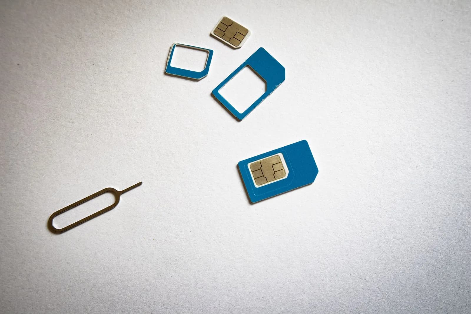 Cartes nano SIM et trombone éjecteur de tiroir SIM posés sur un fond blanc