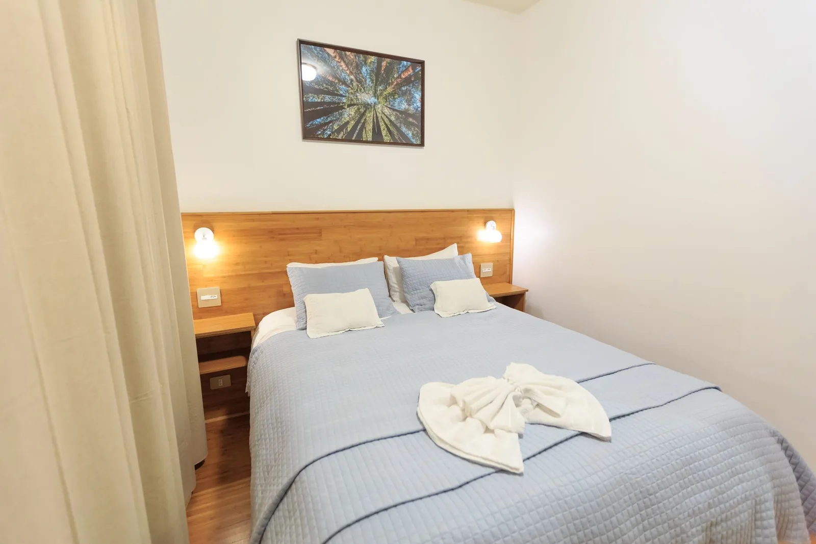 Chambre d'hôtel économique avec lit double, tête de lit en bois et linge bleu clair