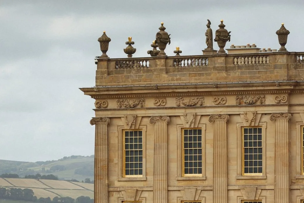 Détail d'une façade baroque en pierre dorée, avec balustrade et urnes