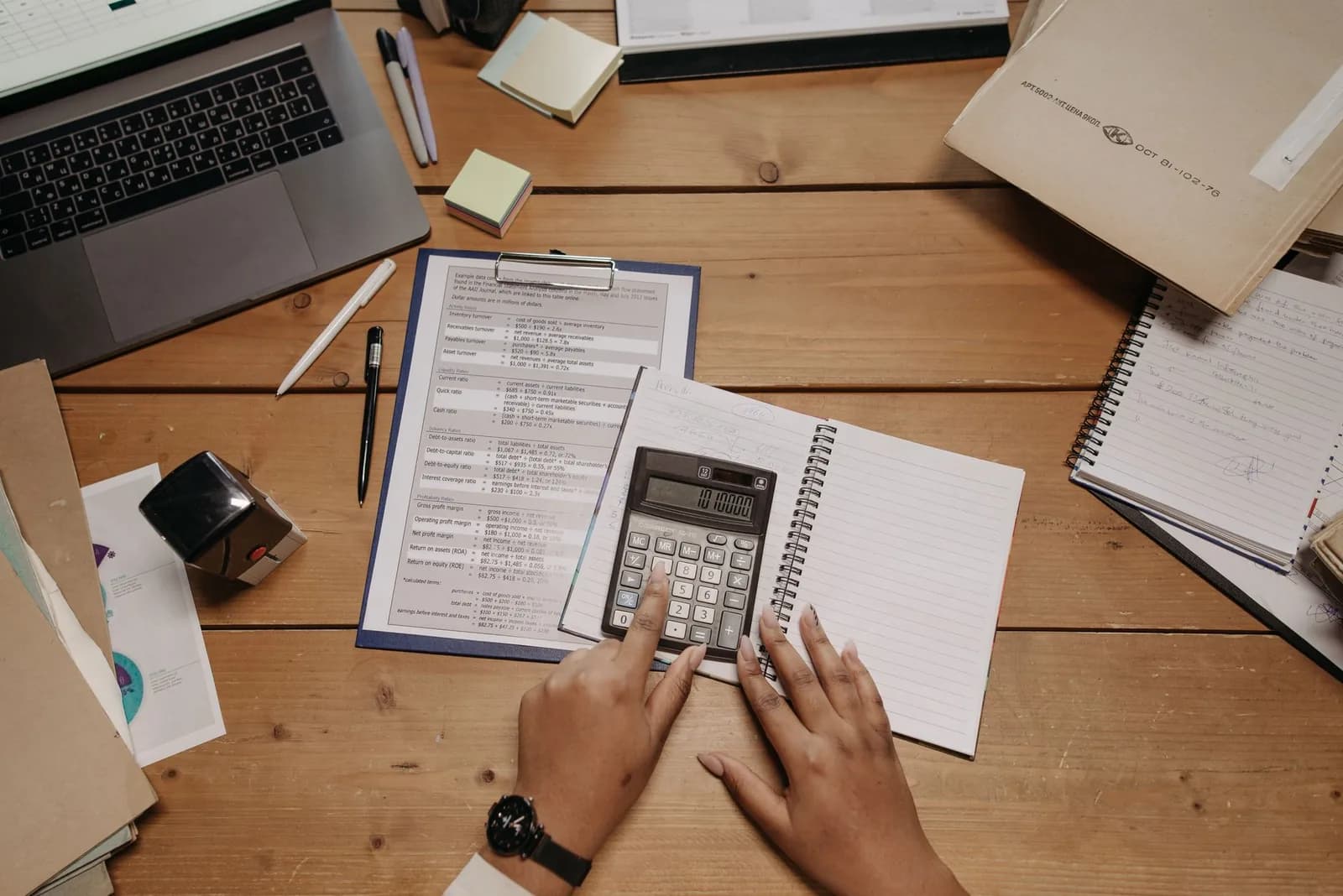 Bureau vu du dessus avec calculatrice, documents comptables, carnet et ordinateur portable