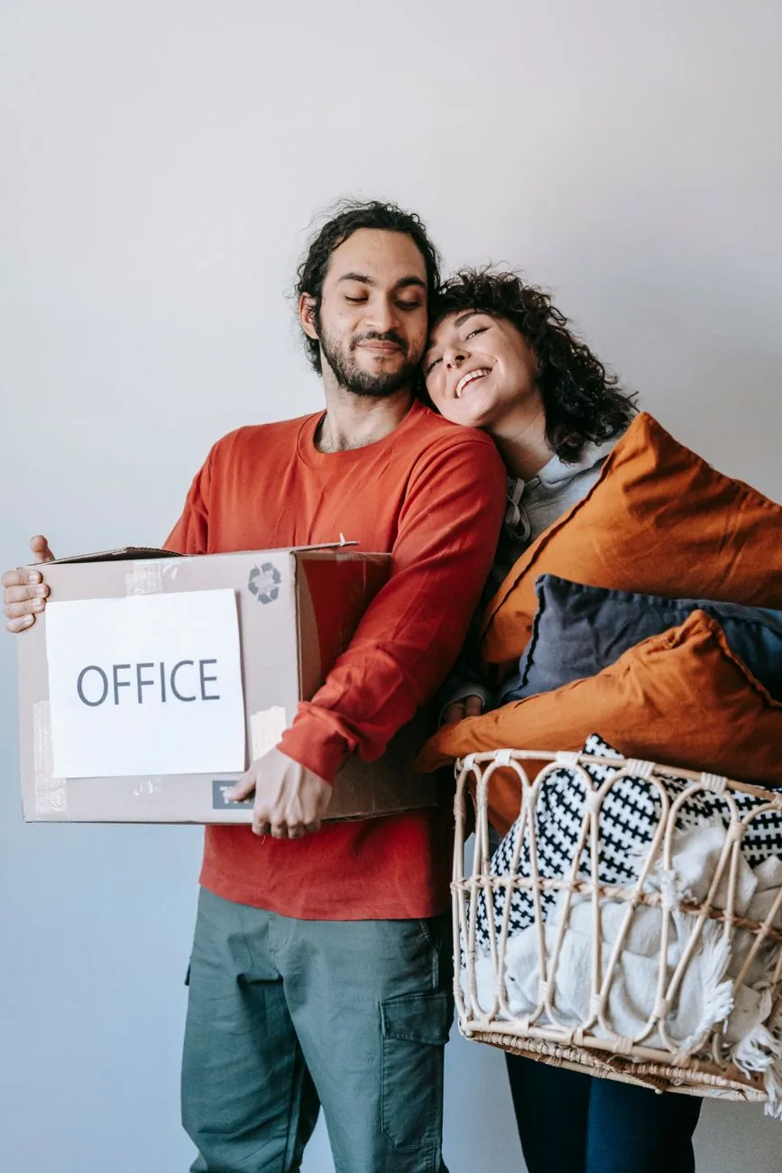 Un couple porte un carton et une corbeille de linge pendant un emménagement
