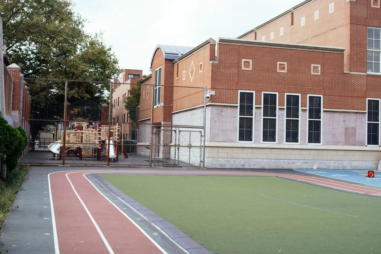 Cour d'école en brique avec une aire de jeux et une piste
