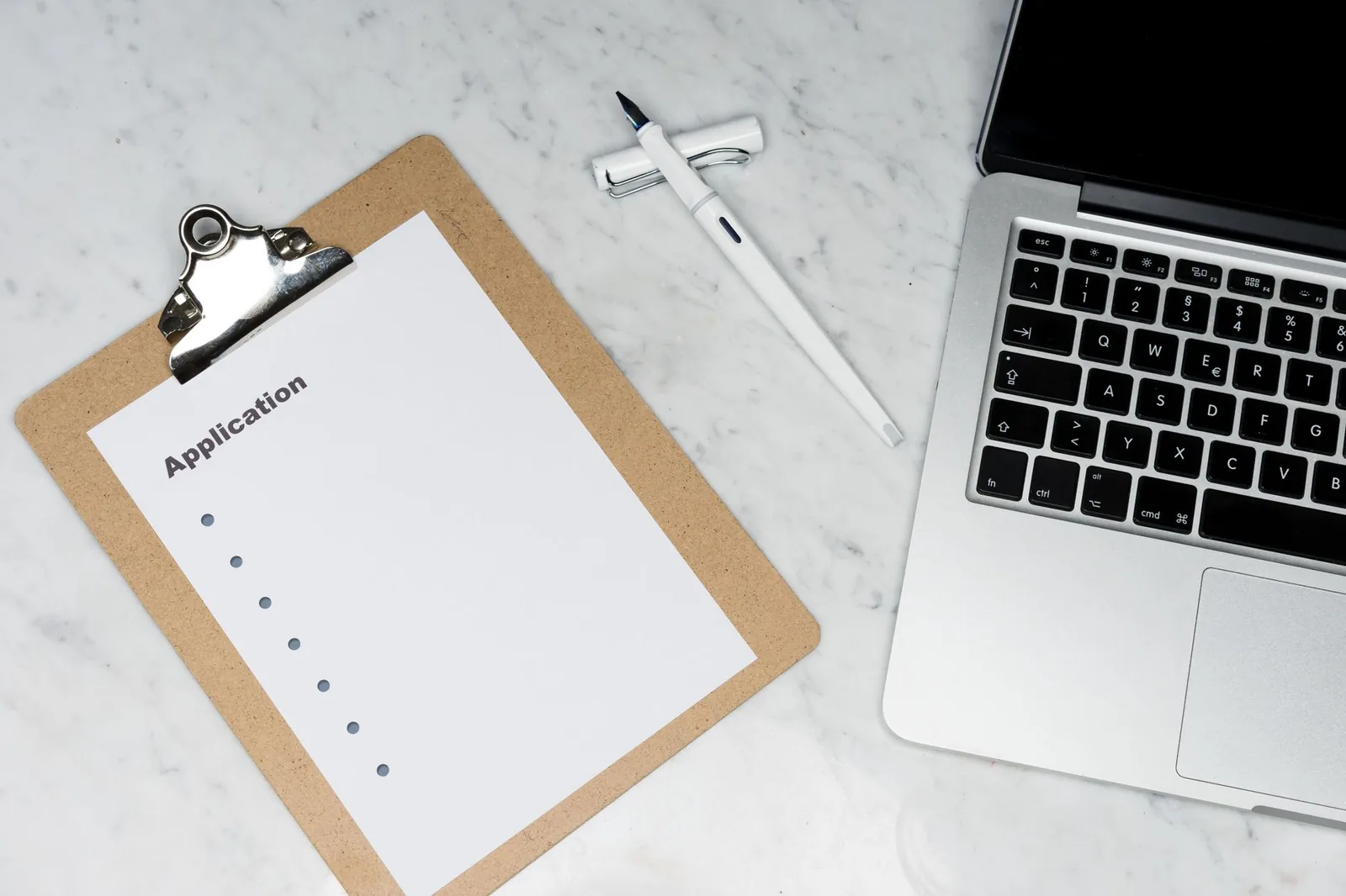 Un formulaire de demande et un ordinateur portable posés sur un bureau
