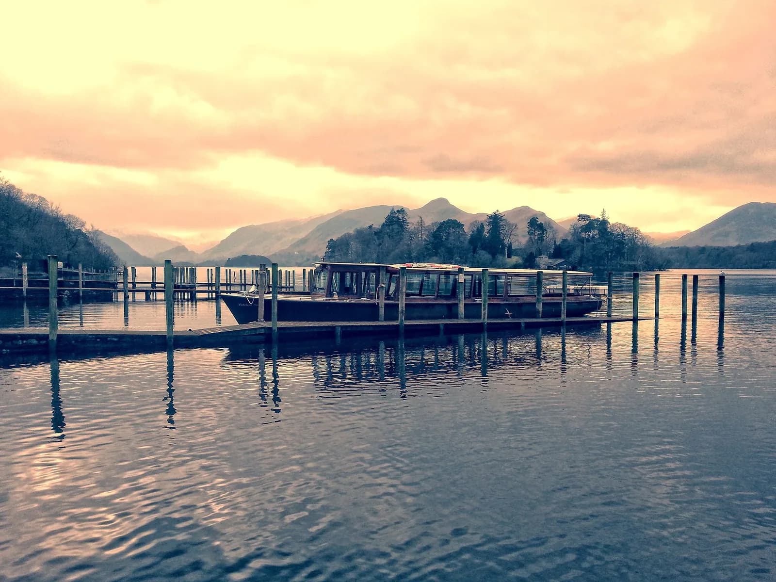Bateau amarré à un ponton sur le lac Derwentwater, près de Keswick, au coucher du soleil