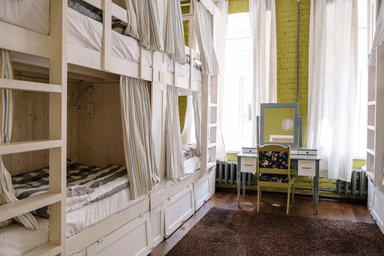 Dortoir d'auberge de jeunesse avec lits superposés en bois blanc munis de rideaux