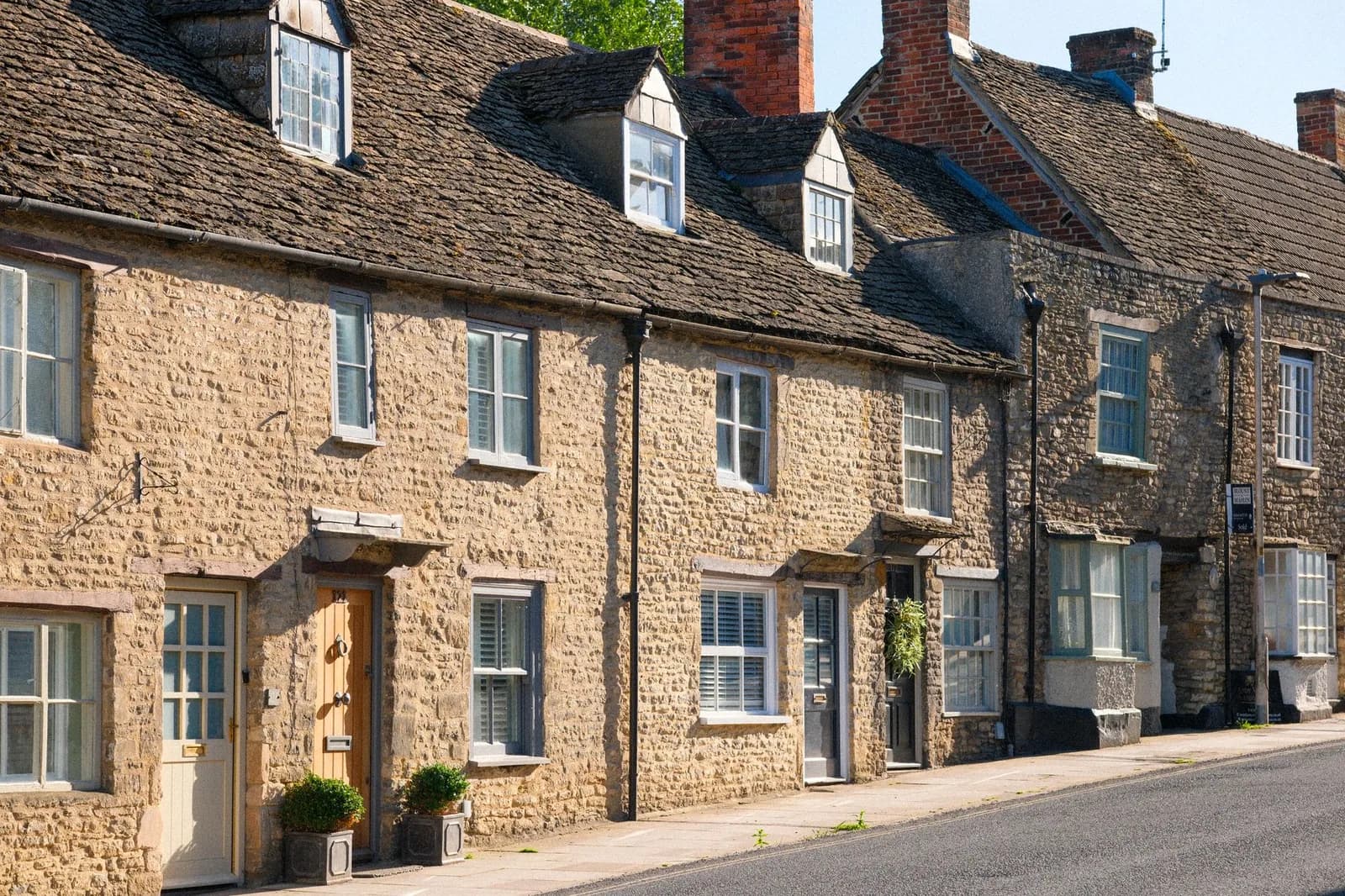 Façades en calcaire clair d'une rangée de maisons dans un village des Cotswolds