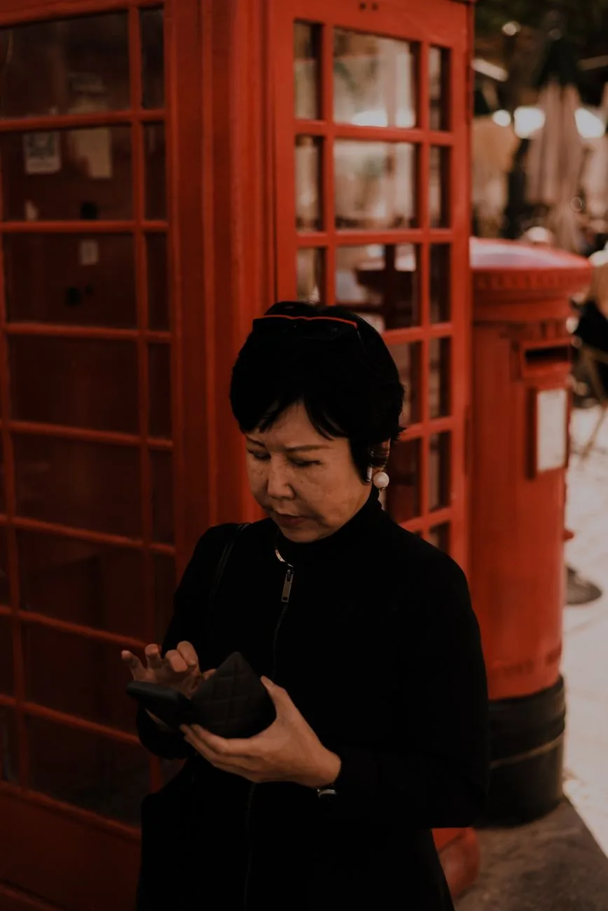 Femme devant une cabine téléphonique rouge et une boîte aux lettres à Londres