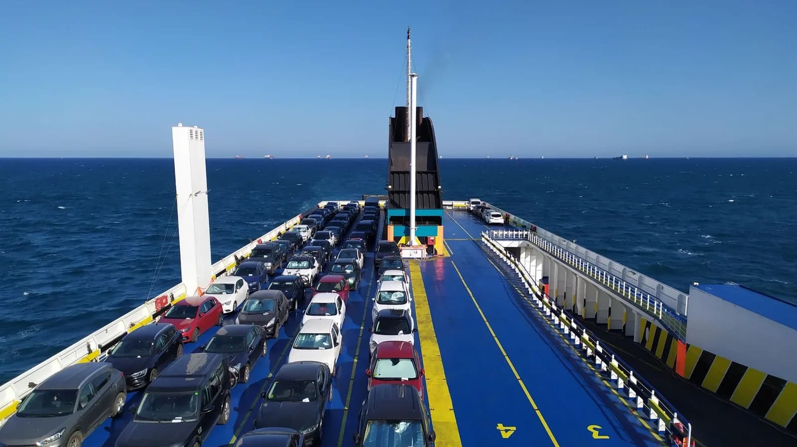 Voitures garées sur le pont d'un ferry en pleine mer, sous un ciel bleu