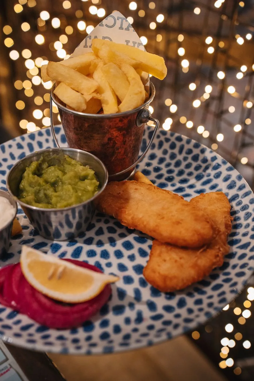 Une assiette de fish and chips accompagnée de mushy peas et d'un quartier de citron