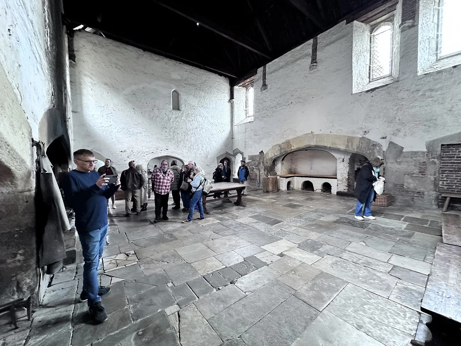 Les cuisines Tudor de Hampton Court, salle voûtée aux tables de bois avec l'âtre au fond