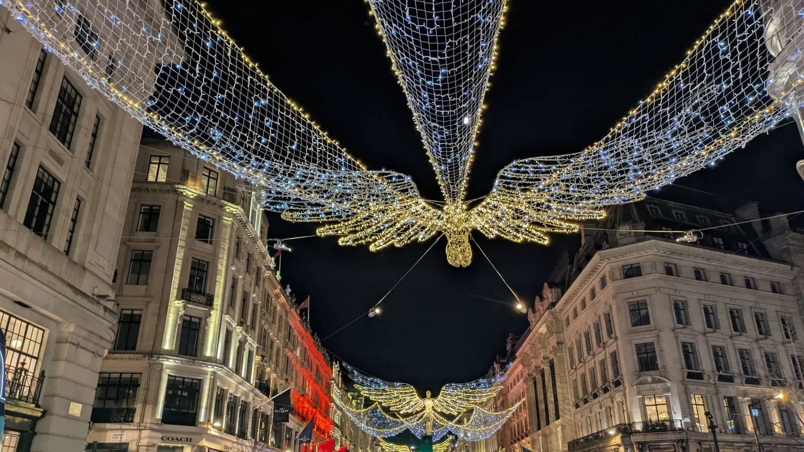 Illuminations de Noël de Regent Street de nuit, anges lumineux suspendus au-dessus des façades, Londres