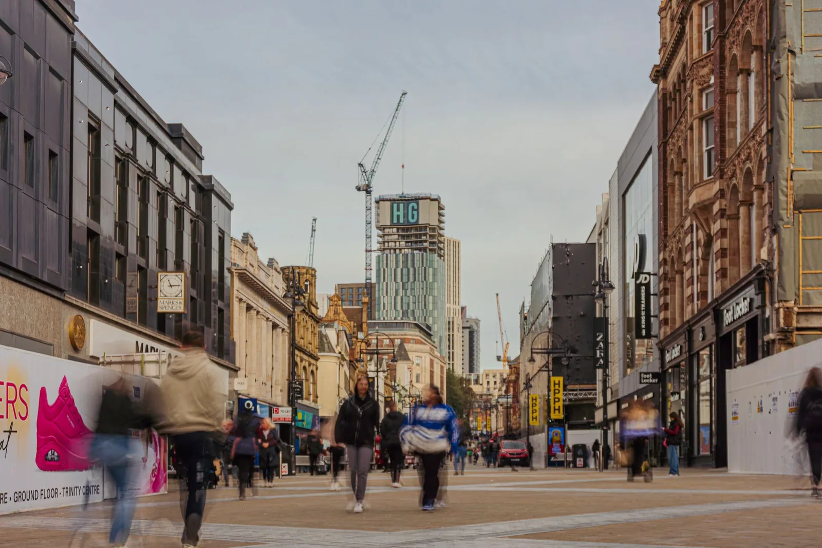 Rue piétonne commerçante dans le centre-ville de Leeds, entre façades victoriennes en brique et immeubles récents
