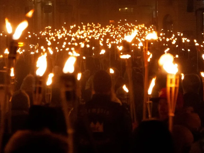 Foule portant des flambeaux enflammés lors d'une procession aux torches, de nuit