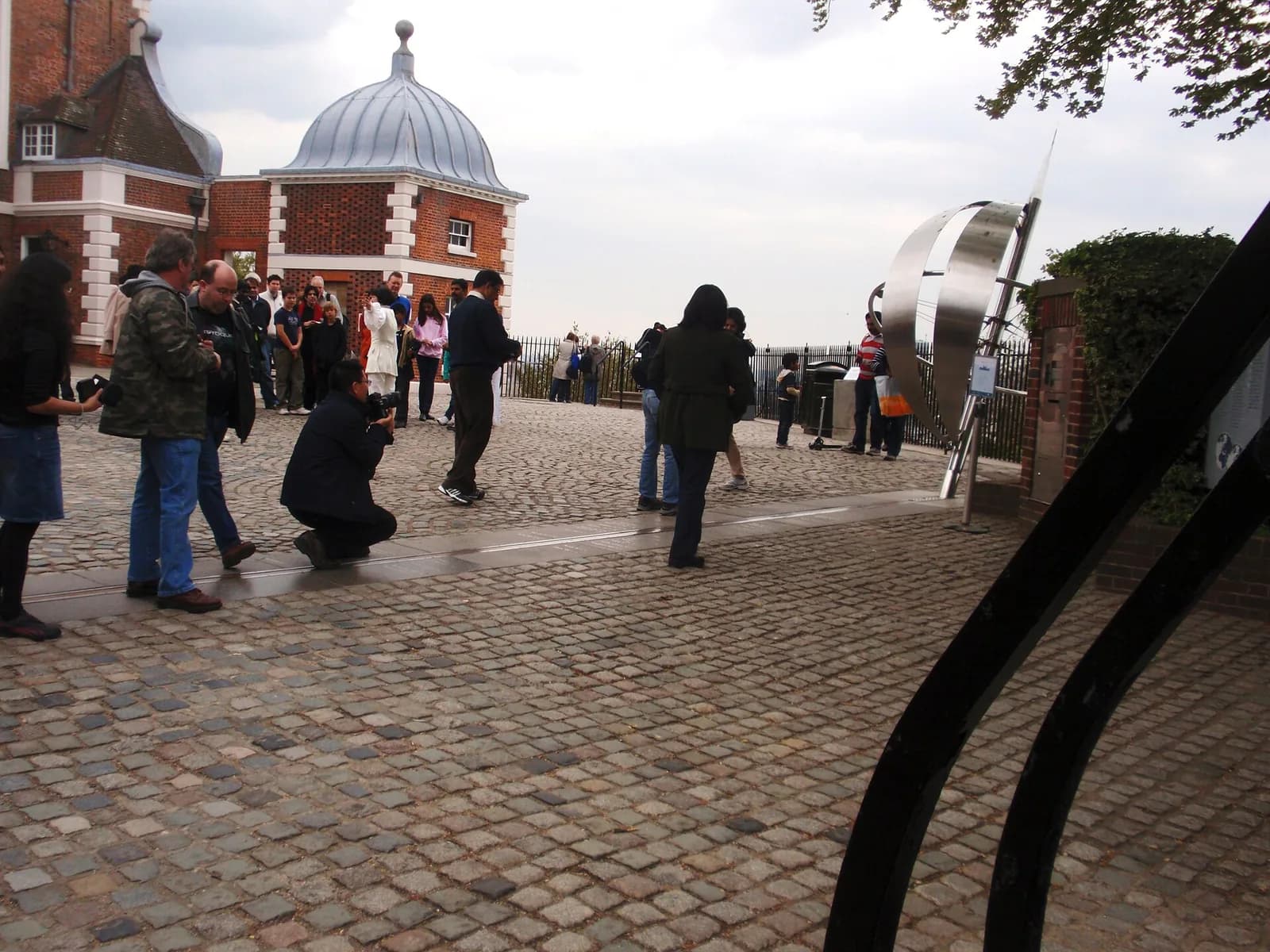 Des visiteurs sur la ligne du méridien d'origine, devant l'Observatoire royal de Greenwich