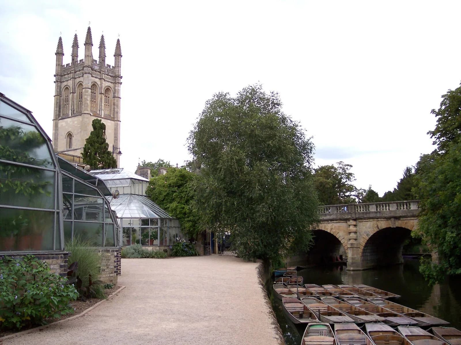 La tour de Magdalen College au-dessus des arbres, avec Magdalen Bridge et des punts sur la Cherwell