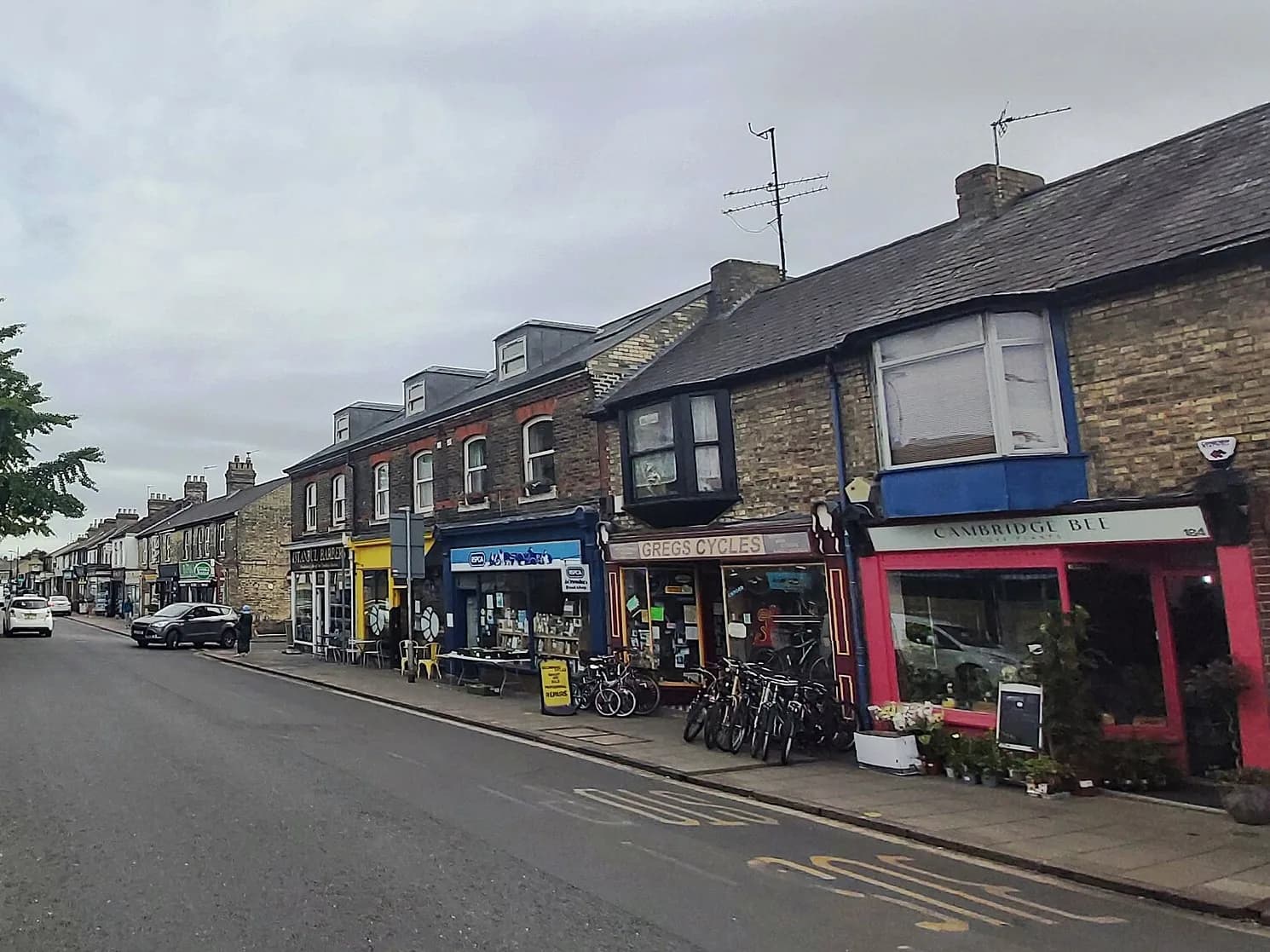Mill Road à Cambridge, avec ses maisons en brique, ses commerces et des vélos garés devant les boutiques