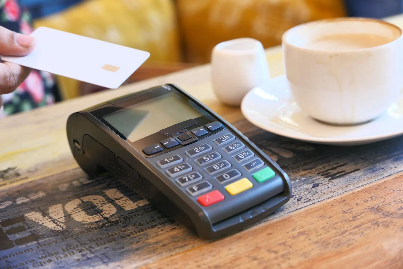 Main présentant une carte bancaire devant un terminal de paiement sans contact