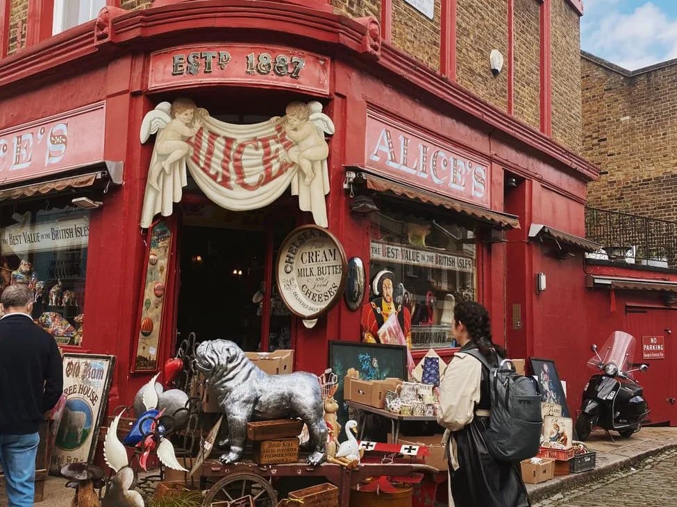 Un étal d'antiquités et de brocante devant une boutique à façade rouge, sur un marché londonien