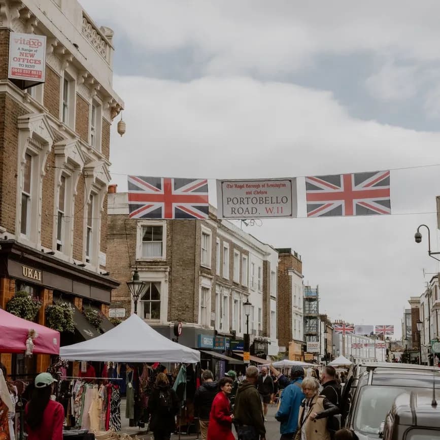 Étals et foule sous une banderole Portobello Road W11, à Notting Hill