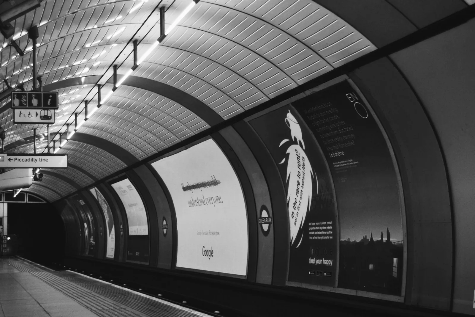 Un quai du métro de Londres, tunnel voûté et panneaux publicitaires