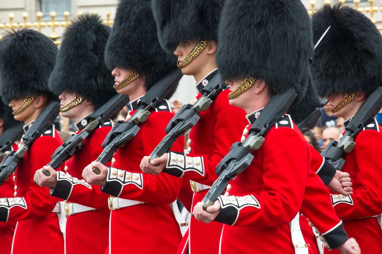 Soldats de la garde en tunique rouge et bonnet en peau d'ours, fusil à l'épaule, en marche rapprochée