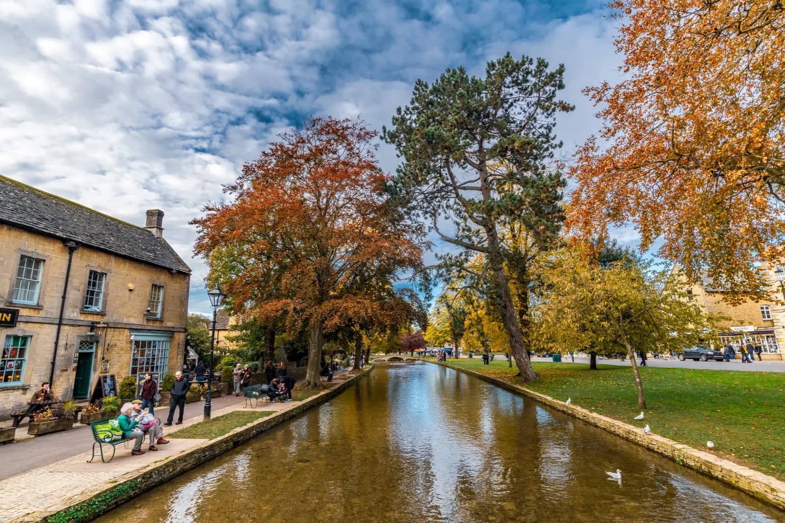 La rivière Windrush bordée de pelouses et d'arbres d'automne à Bourton-on-the-Water