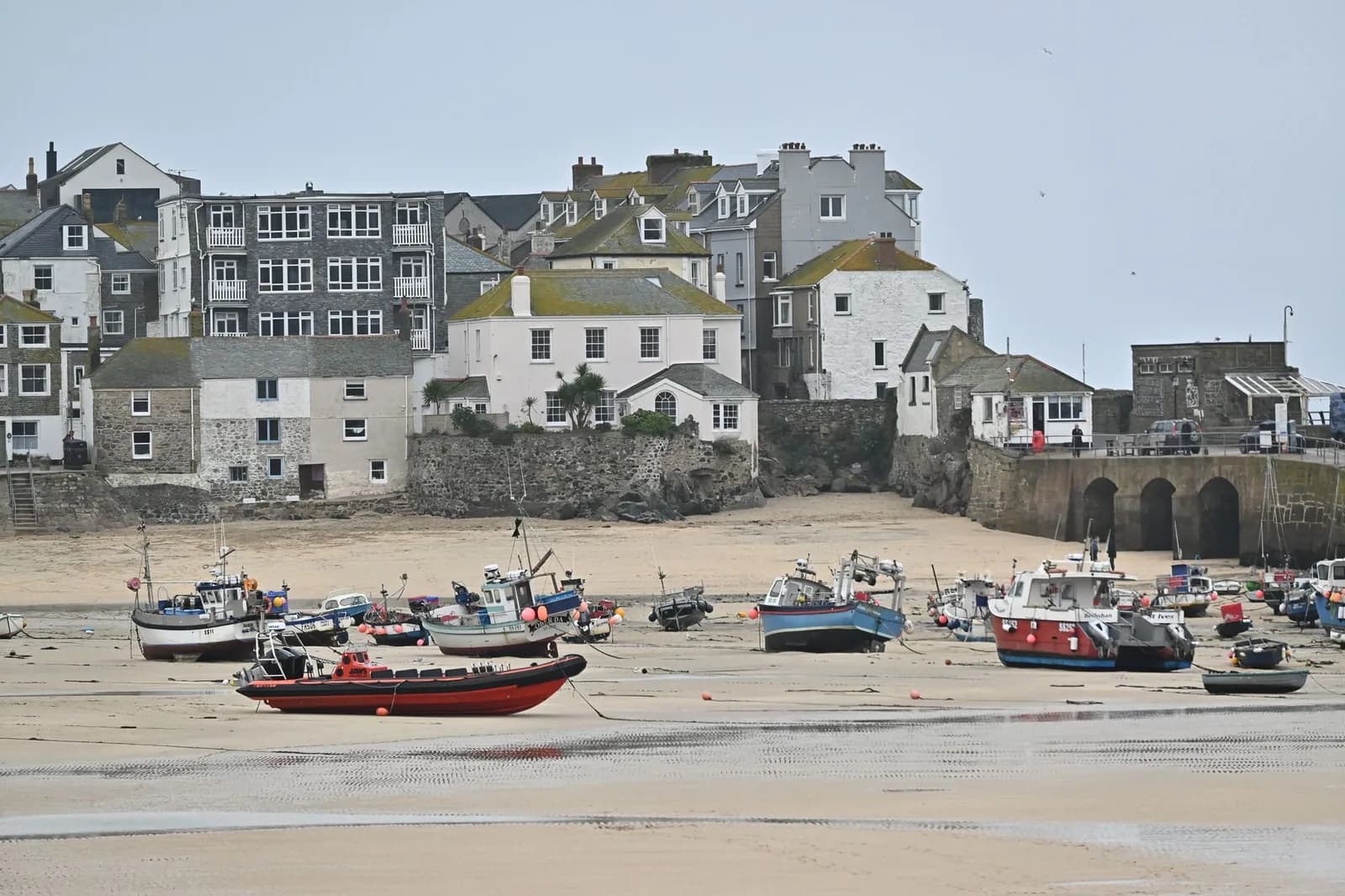Bateaux de pêche échoués sur le sable à marée basse devant les maisons du port de St Ives