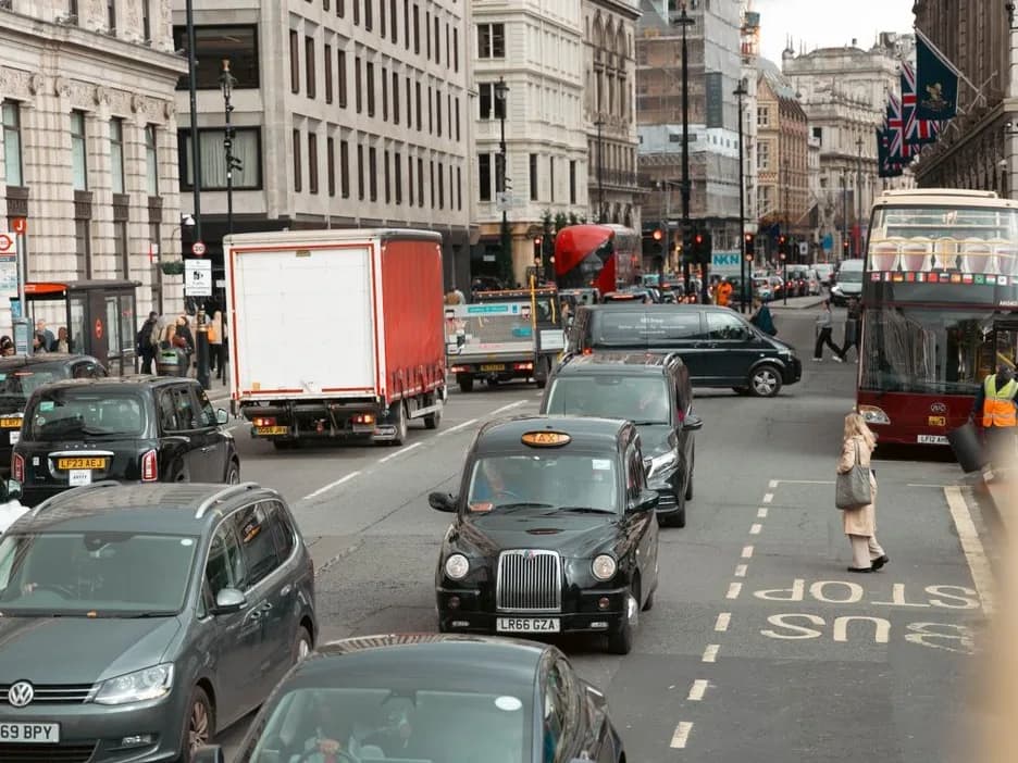 Circulation dense dans le centre de Londres, avec taxis noirs, voitures, camion et bus rouge à impériale
