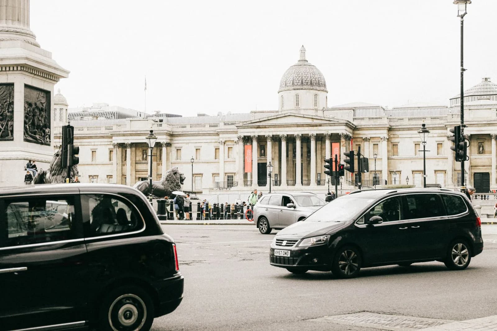 Trafalgar Square à Londres : le socle de la colonne de Nelson, des taxis noirs et la façade de la National Gallery