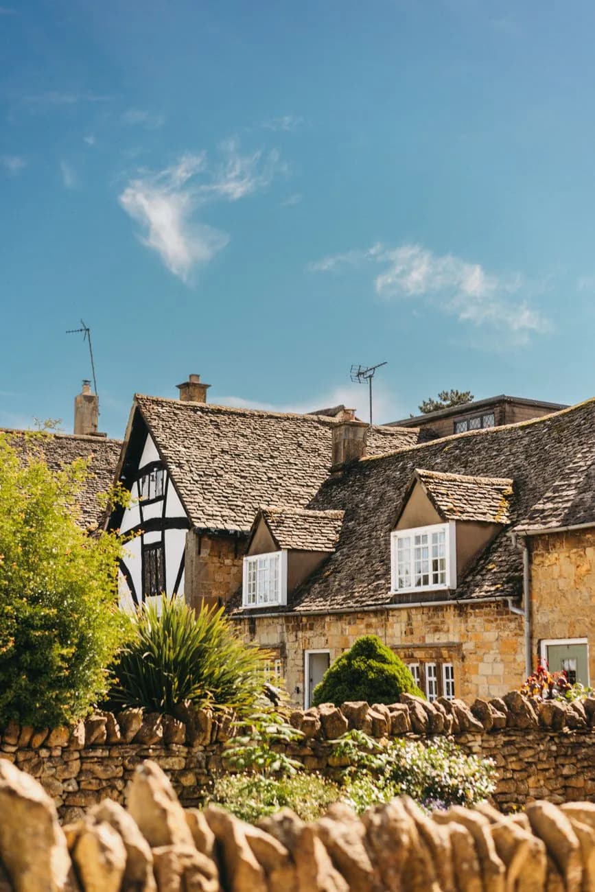 Maisons en pierre calcaire dorée et muret de pierre sèche dans un village des Cotswolds
