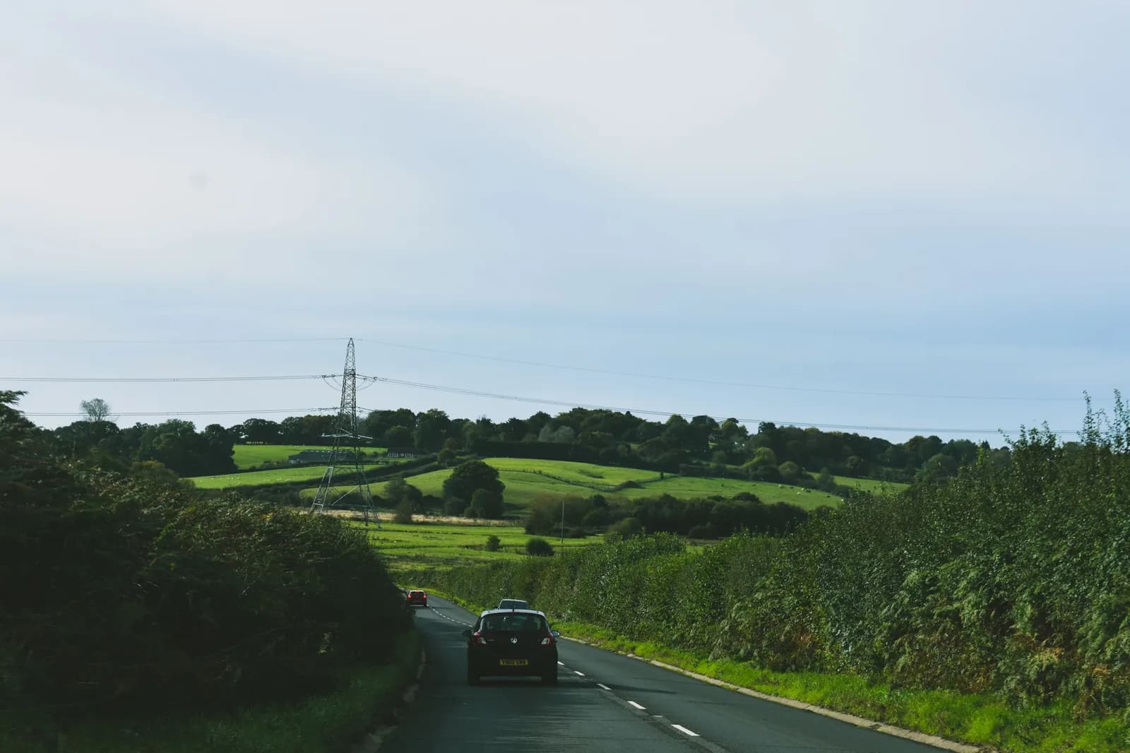 Voiture roulant à gauche sur une route de campagne bordée de haies en Angleterre