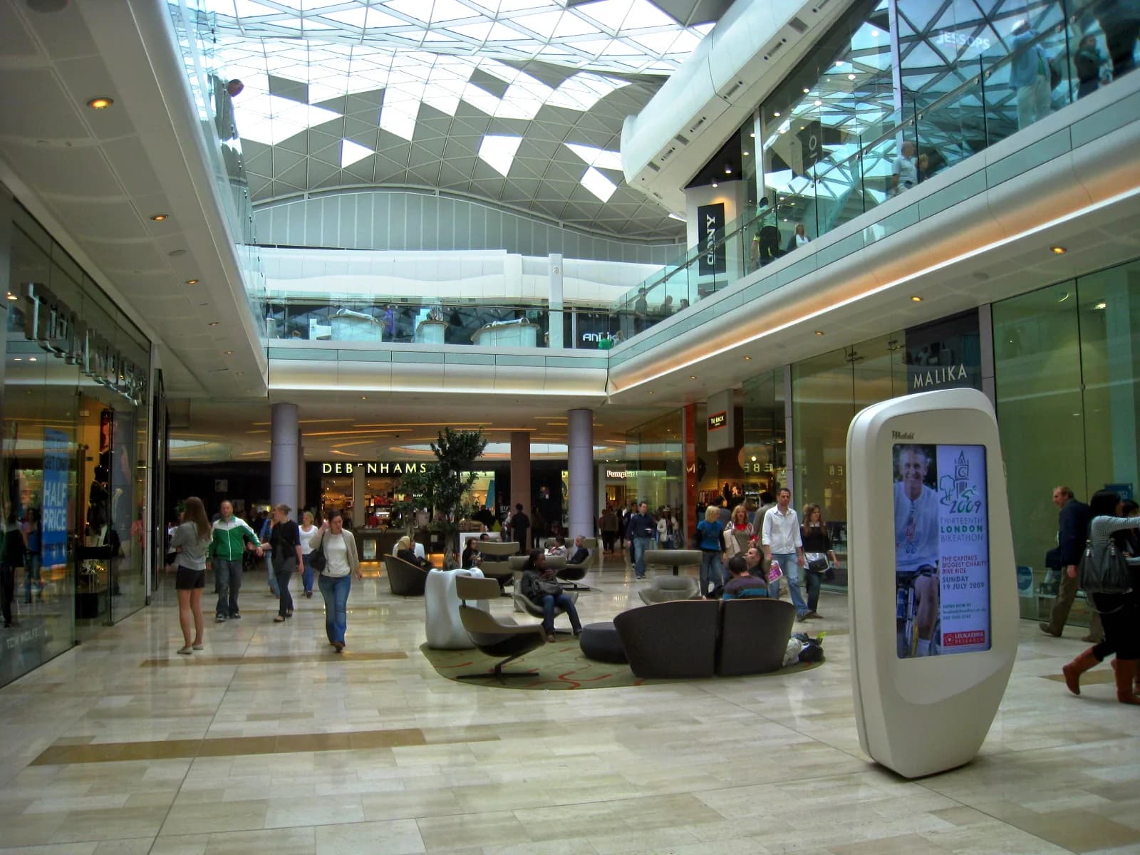 Galerie intérieure du centre commercial Westfield London, avec sa verrière, ses boutiques et des visiteurs