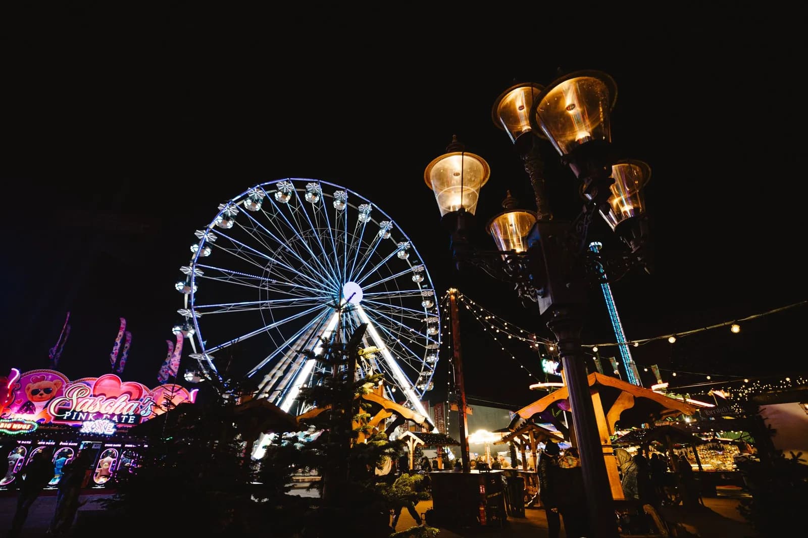 Grande roue illuminée et manèges lumineux d'une fête foraine de Noël, de nuit